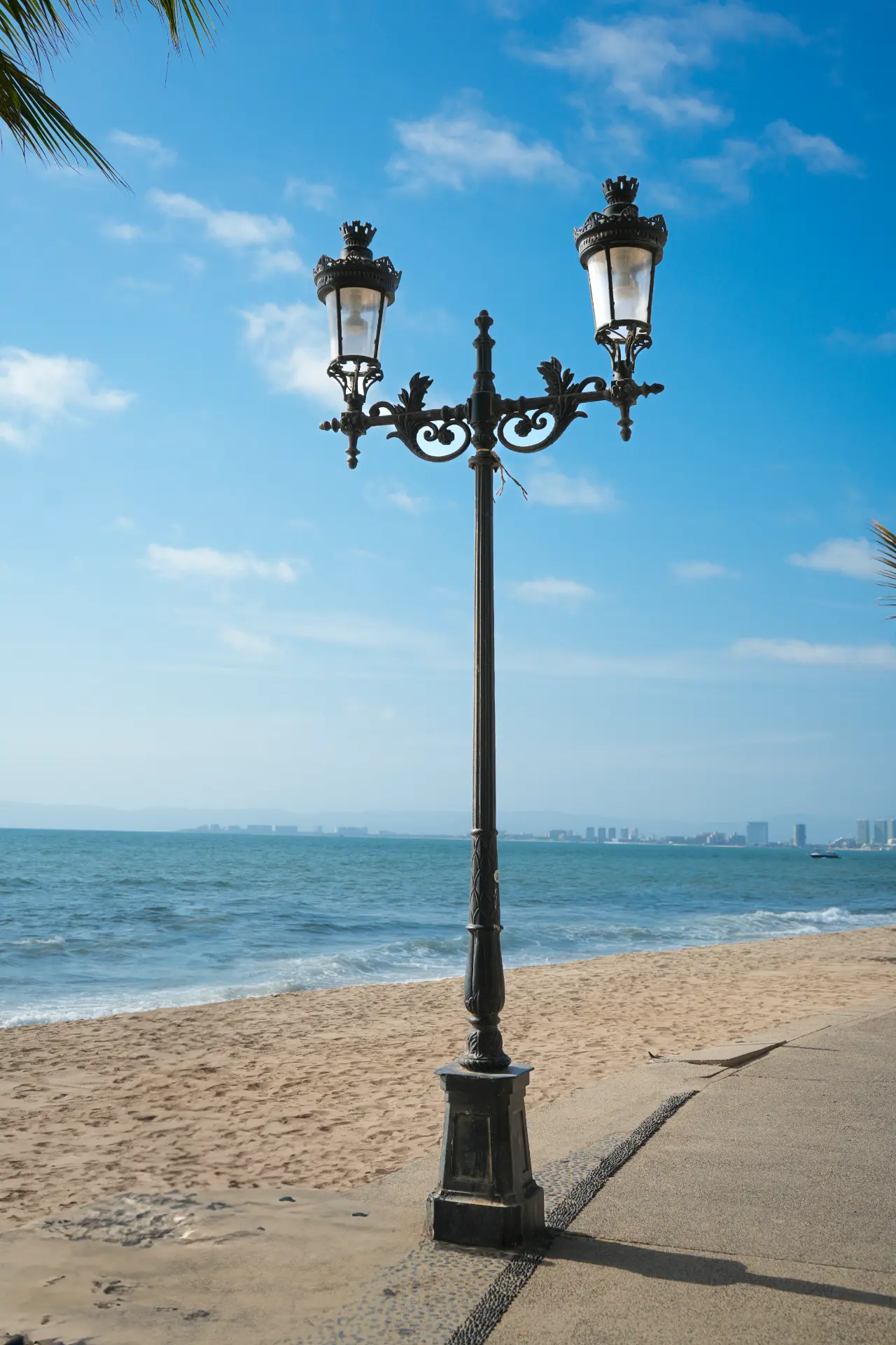 Poste ornamental con dos luminarias frente al mar